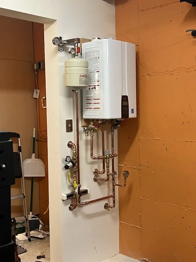 Plumbing technician inspecting water heater connections in Denville